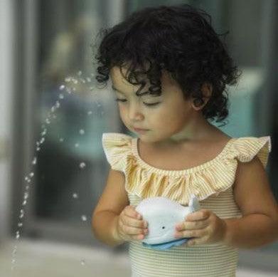 Child playing with Hevea Squeeze'N'Splash blue whale bath toy.