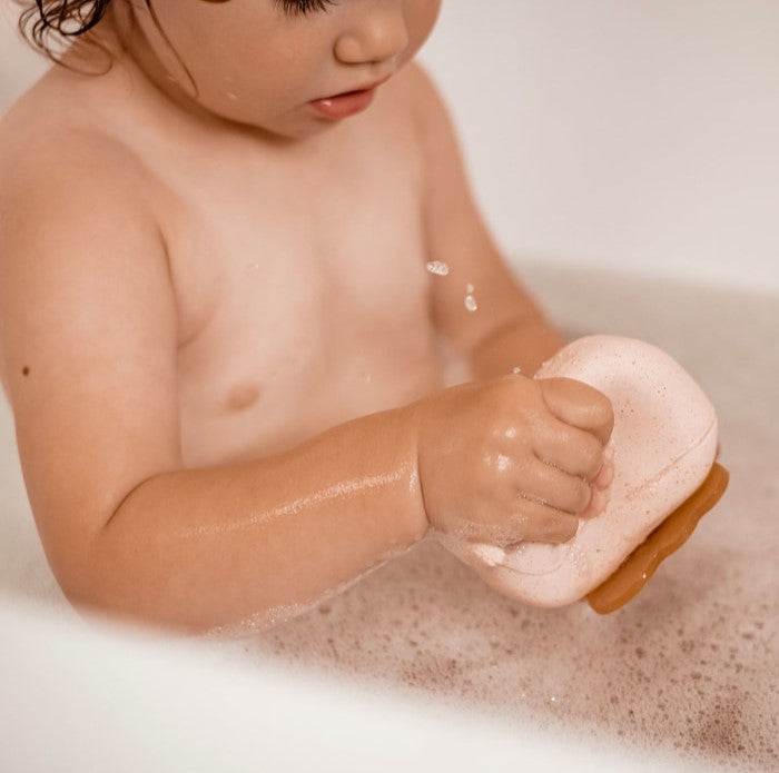 Child playing with Hevea Squeeze'N'Splash bath toy in a tub.