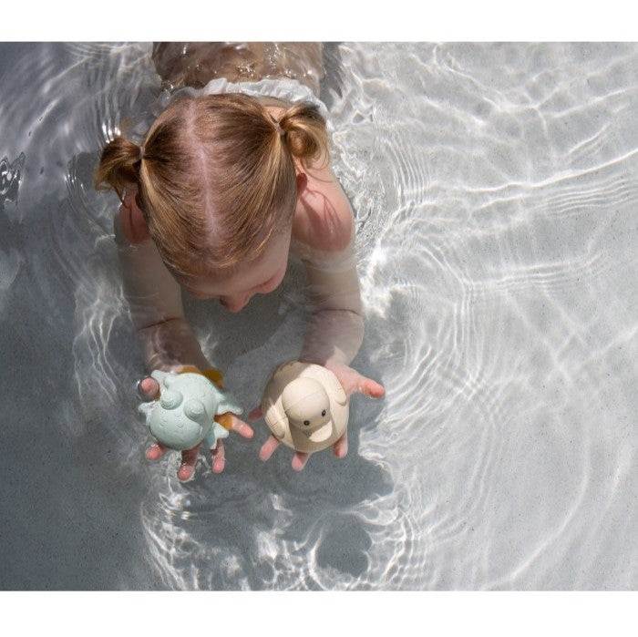 Child playing with Hevea Squeeze'N'Splash bath toys, blue duck and sage frog, in water.