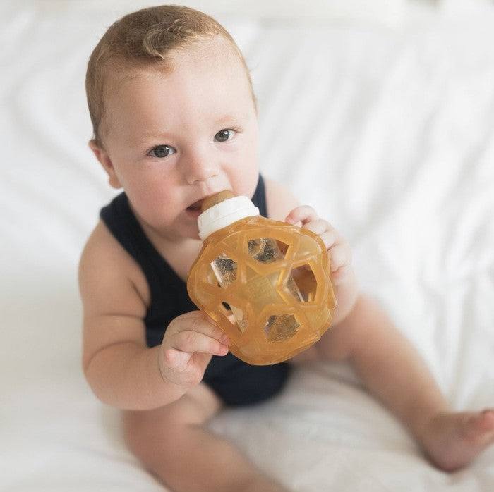 Baby holding Hevea staklena flašica with Star Ball cover, eco-friendly design.
