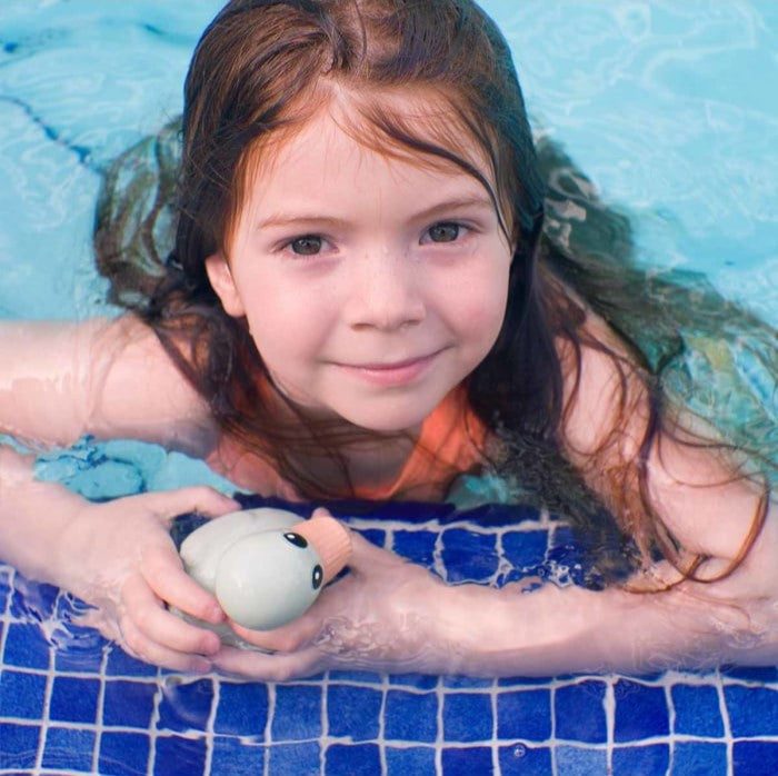 Child playing with Hevea Kawan Mini rubber duck in a pool.