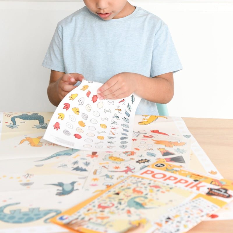 Poppik Kreativni posteri: Dinosaursi 3+ with child decorating with stickers.
