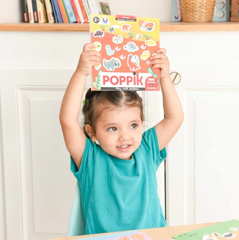 Poppik Moje prve nalepnice set held by a smiling child at a table.
