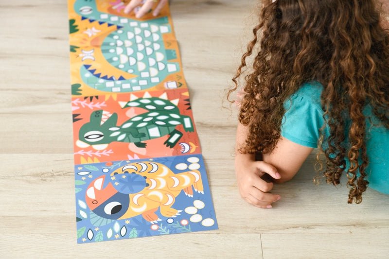 Child engaging with colorful dinosaur sticker panorama on the floor.