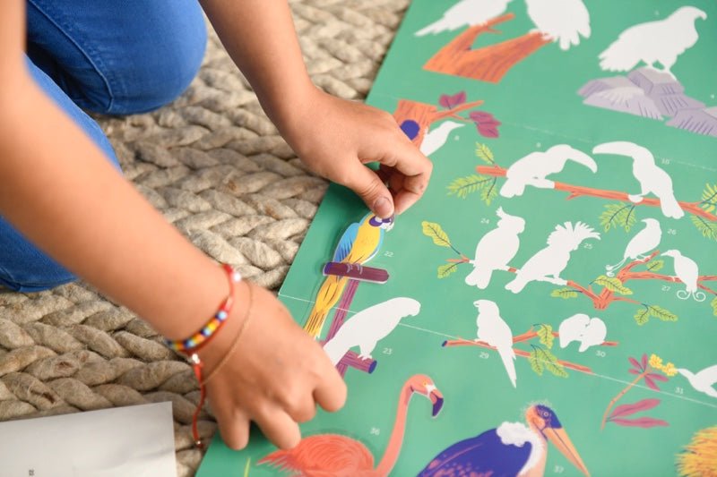 Child placing bird sticker on Poppik educational poster.