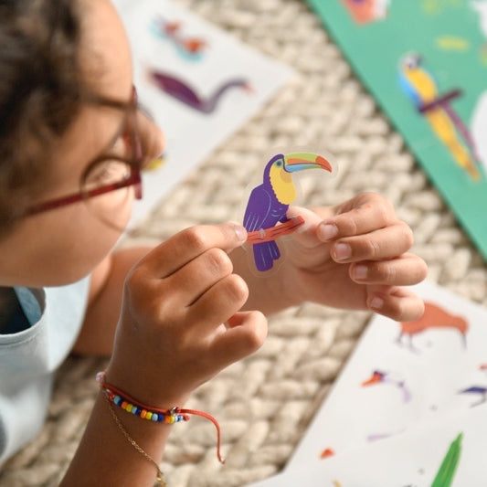 Child arranging bird stickers on Poppik educational poster.