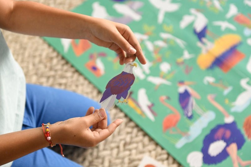 Child placing bird sticker on Poppik Edukativni poster.