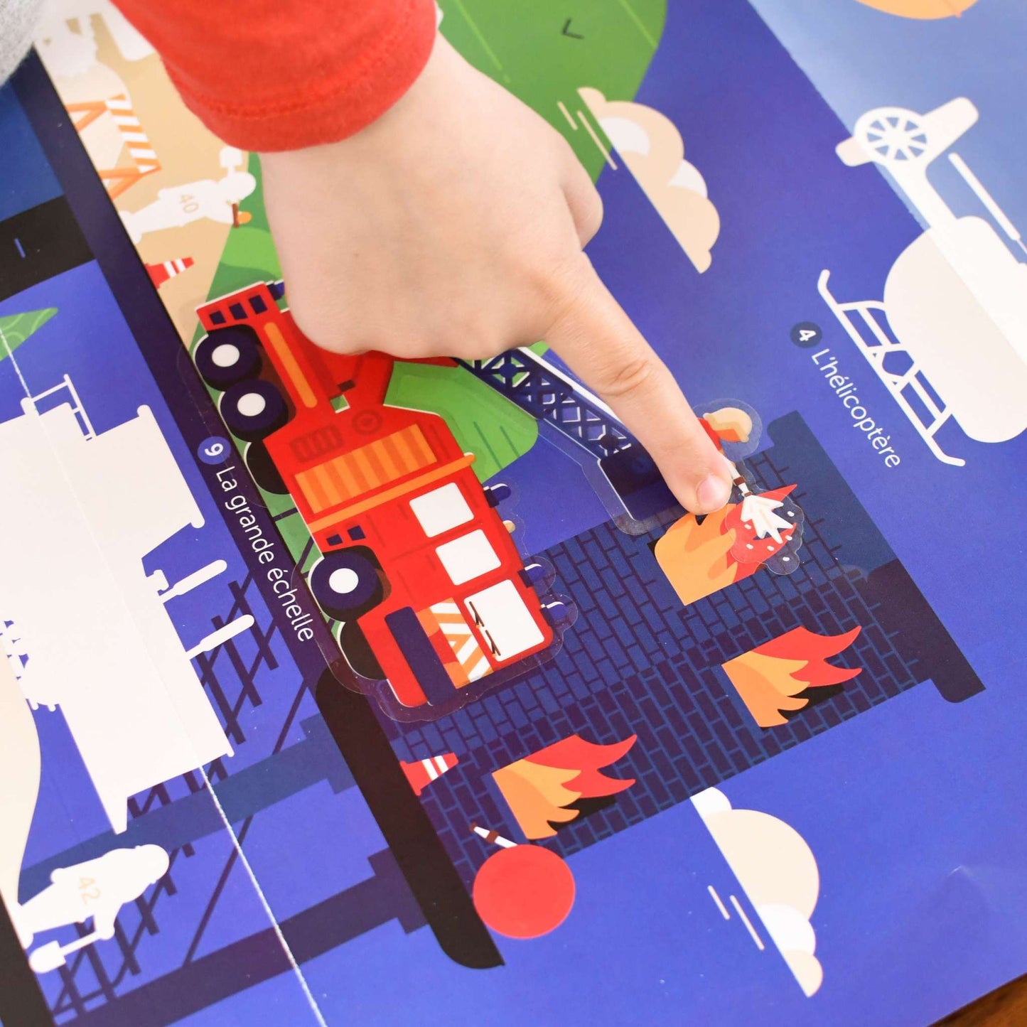 Children placing vehicle stickers on educational poster with various languages.