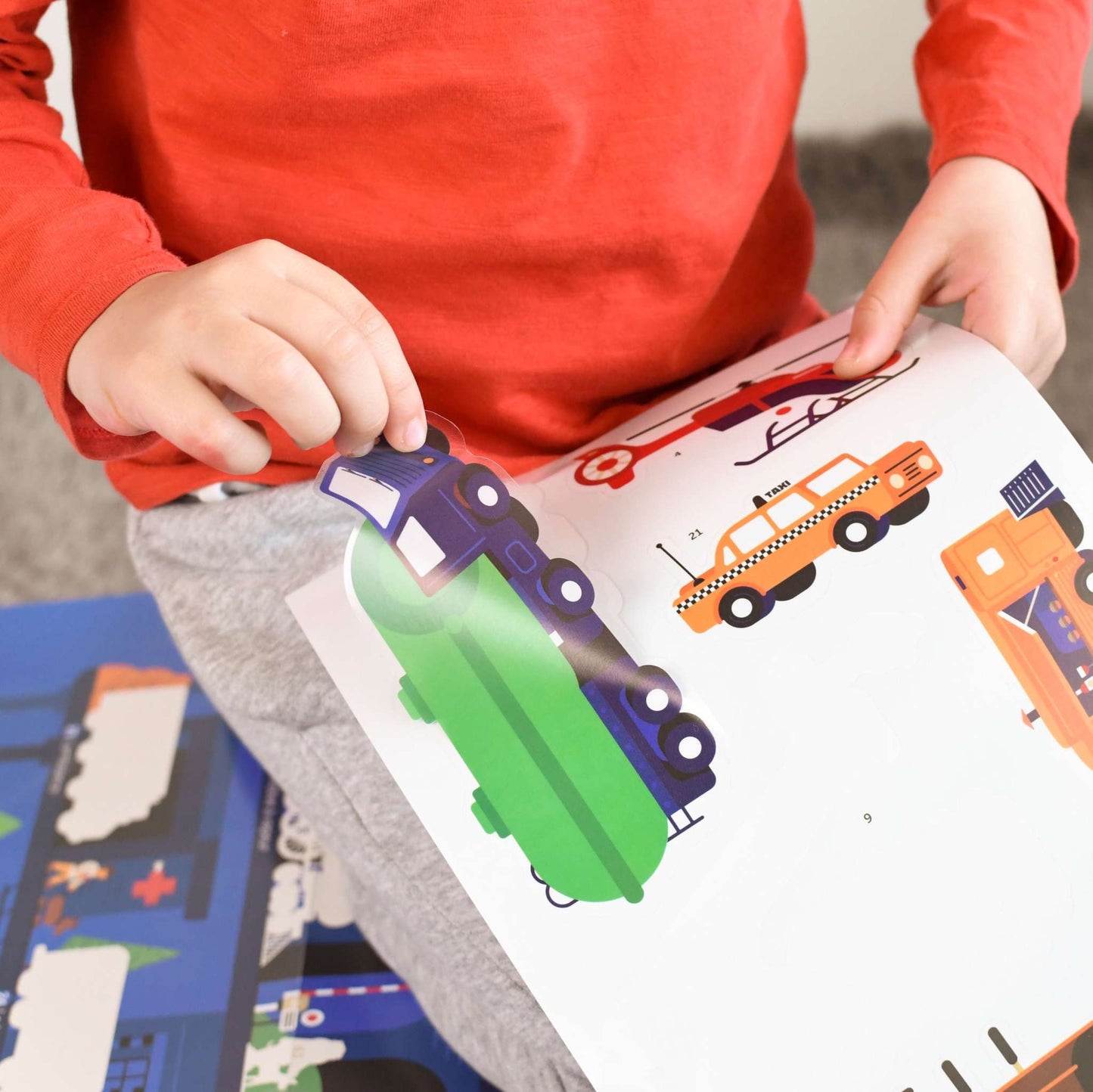 Child placing vehicle stickers on Poppik educational poster.