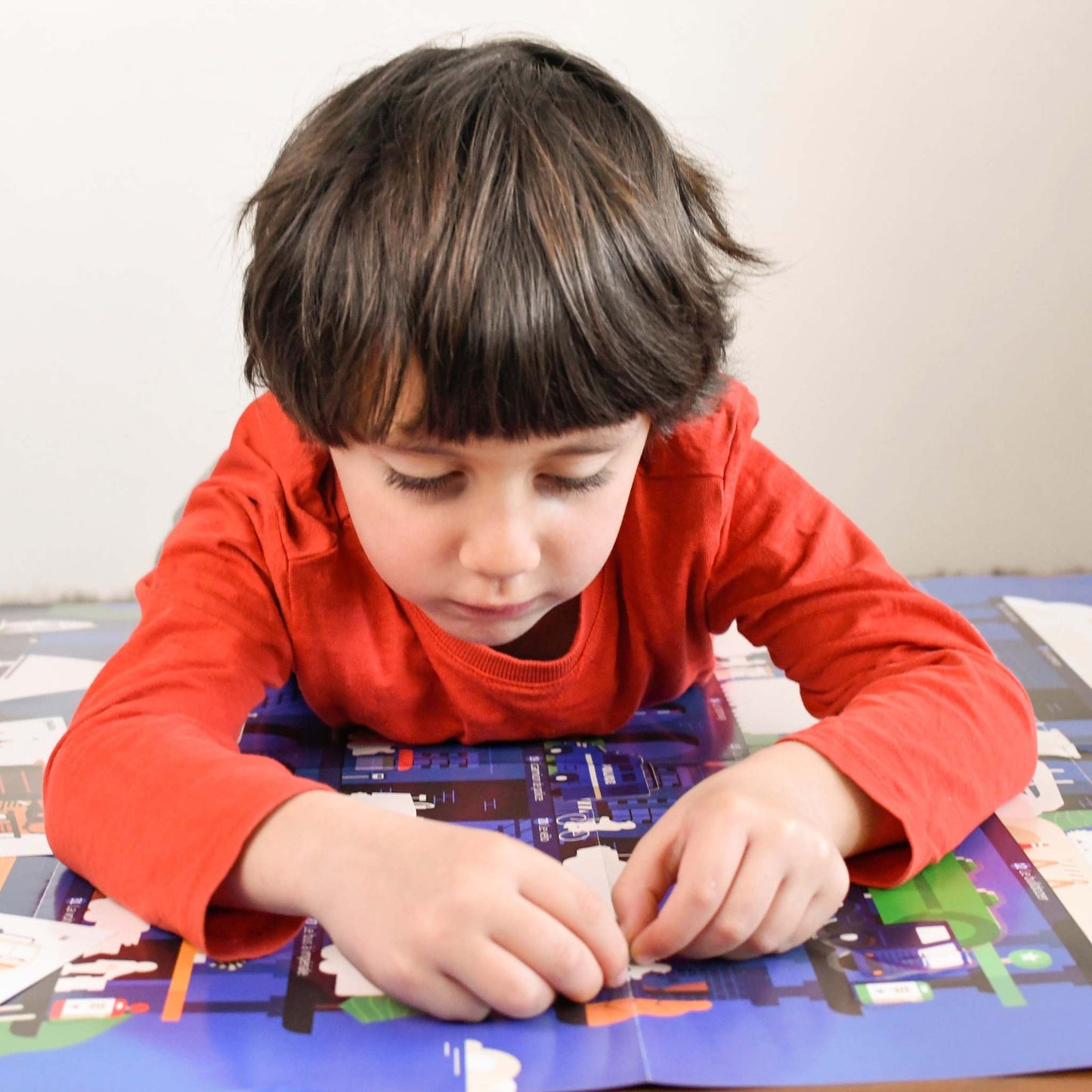 Child playing with Poppik Edukativni poster sa nalepnicama Otkrića: Vozila, adding vehicle stickers.