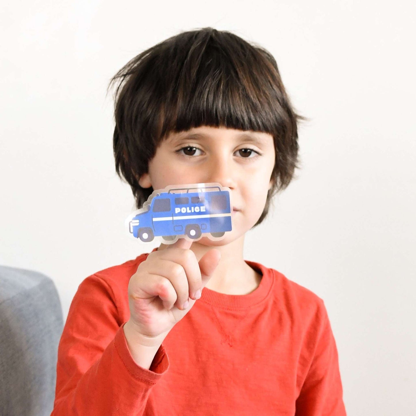 Child holding sticker from Poppik Edukativni poster Vozila 4+, featuring various vehicles.