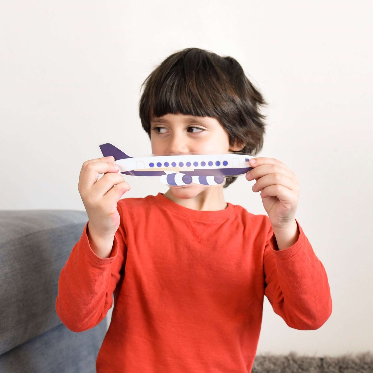 Child holding airplane sticker from Poppik educational vehicle poster.
