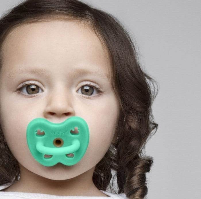 Hevea okrugla natural rubber pacifier in pop green on child.