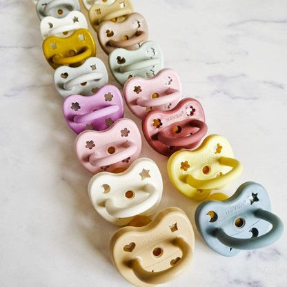 Hevea natural rubber pacifiers for ages 3-36 months, orchid and sand colors, soft and gentle for baby's face and lips.