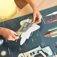 Child placing a sticker on an educational astronomy poster featuring planets, stars, and astronauts.